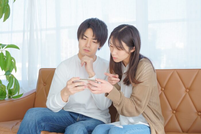 住宅ローンの返済についてスマホを見ながら相談する夫婦