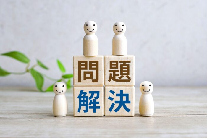 不動産の決済トラブルの問題解決を表す木製ブロックと売主・買主・関係者の人形